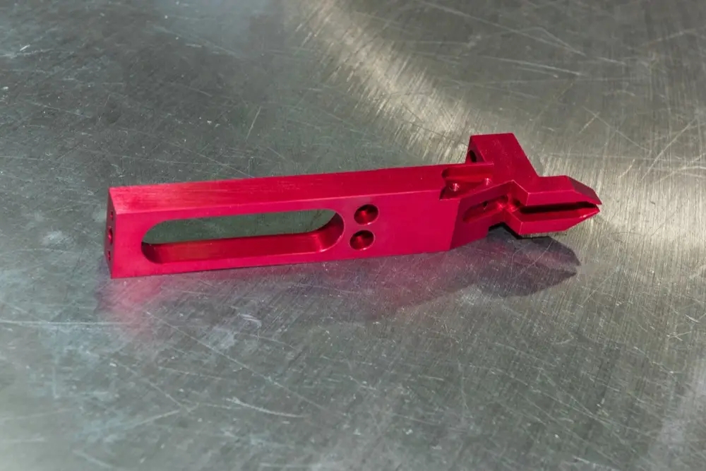 Red machined kick-out arm for a label printing machine